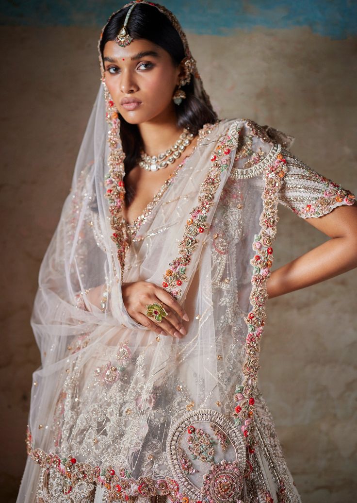 Ivory raw silk bridal lehenga with thread and pearl embroidery paired with two tulle dupattas and an embroidered blouse. Off White Wedding Sets With Dupatta, Bollywood Style Off White Sharara For Wedding, Bollywood Pearl Embroidered Dupatta For Reception, Wedding Saree With Pearl Embroidery And Traditional Drape, Off White Sharara With Sheer Dupatta For Reception, Off-white Sharara With Sheer Dupatta For Reception, Wedding Anarkali Set In Raw Silk With Pearl Embroidery, Traditional Drape Off White Lehenga For Wedding, Off White Traditional Drape Lehenga For Wedding