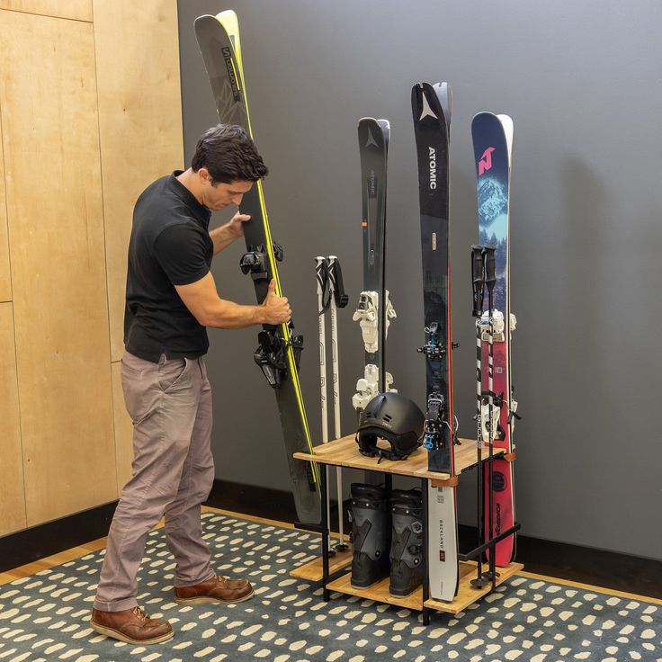 a man standing in front of a rack with skis and snowboards on it