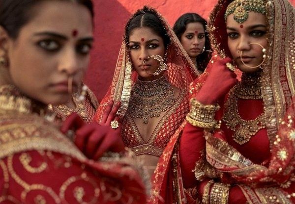 three women dressed in red and gold are posing for the camera