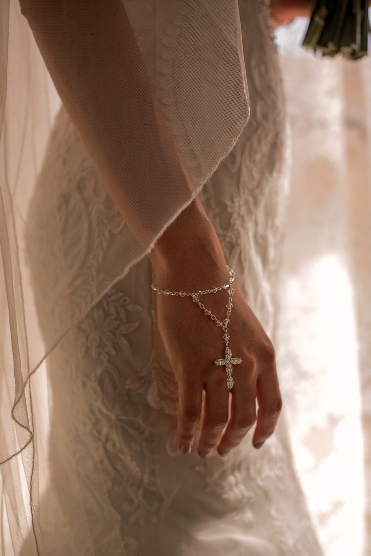 a close up of a person wearing a wedding dress and holding a cross on her hand