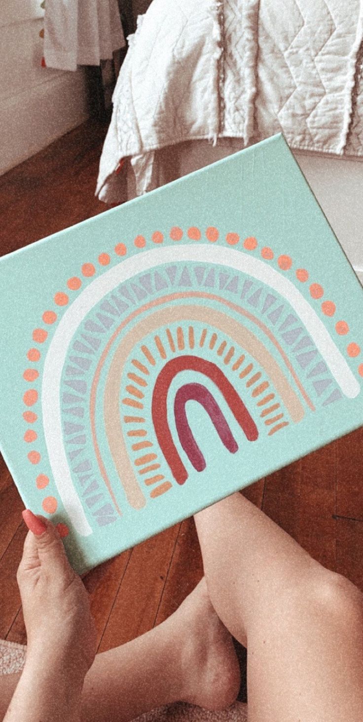 a person laying on the floor holding up a box with an image of a rainbow in it