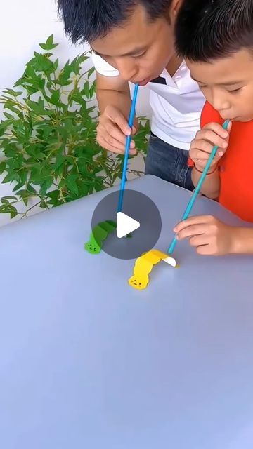 two boys are brushing their teeth with toothbrushes on a table in front of plants