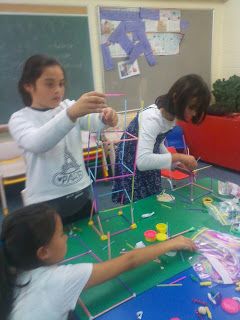 three girls are playing with toys on a table in a classroom at the elementary school