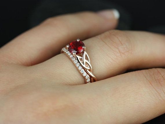 a woman's hand with a ring on it and a red stone in the middle