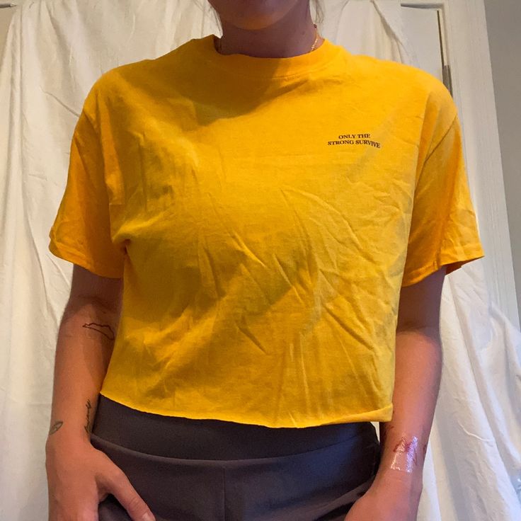 Bought 5 Years Ago From Urban Outfitters, Never Worn With The Tag. Details: Only The Strong Survive Printed In Navy On The Back And In The Corner On The Front. The Shirt Is A Mustard Yellow Color. It Has A Raw Cut Hem And Was Purchased The Way So It Is Definitely Cropped Evenly. Fit: Fits True To Size. I Am 5’3 And The Crop Hits About At My Bellybutton. Yellow Fitted Crew Neck Top, Casual Mustard Top With Graphic Print, Mustard Casual Top With Graphic Print, Yellow Cotton Crew Neck Top, Yellow Cotton Short Sleeve Crop Top, Yellow Cotton Crop Top With Short Sleeves, Yellow Relaxed Fit Short Sleeve Tops, Yellow Cropped Cotton Crop Top, Yellow Short Sleeve Tops With Relaxed Fit