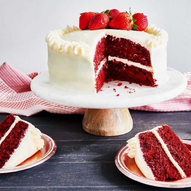 two slices of red velvet cake with white frosting and fresh strawberries on top