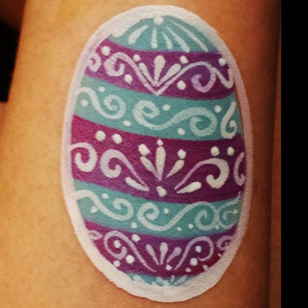 an easter egg painted on the side of a woman's leg with purple and blue stripes