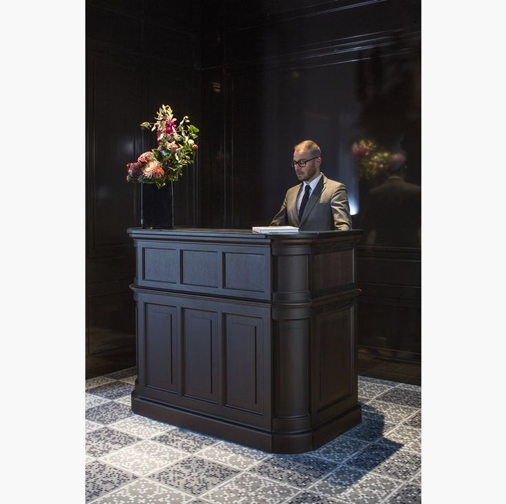 a man standing behind a desk with flowers on it