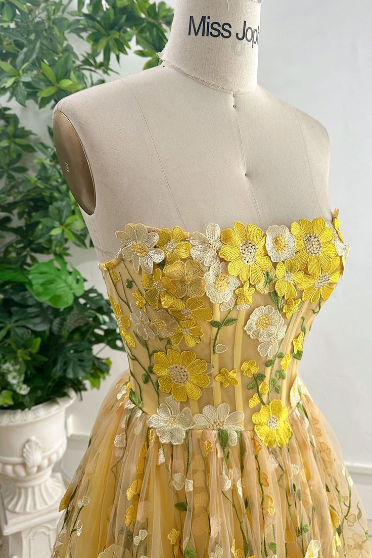 Indulge in pure luxury with our Strapless Corset Yellow Floral Embroidered Midi Dress. Adorned with delicate floral embroidery, this dress is perfect for special occasions or nights out. The strapless design adds a touch of sophistication, while the corset detail creates a flattering silhouette. Elevate your wardrobe and make a statement with this exquisite piece. Bust and Skirt with full lining. 100% Polyester 100% Recycled polyester lining Concealed zip at centre back Imported Spring Gown With Floral Applique And Fitted Bodice, Spring Floral Embroidered Fitted Gown, Spring Banquet Gown With Floral Applique, Spring Gown With Floral Embroidery And Sweetheart Neckline, Spring Prom Gown With Embroidery, Fitted Summer Gown With Floral Applique, Summer Fitted Gown With Floral Applique, Fitted Floral Applique Summer Gown, Spring Organza Gown With Floral Embroidery