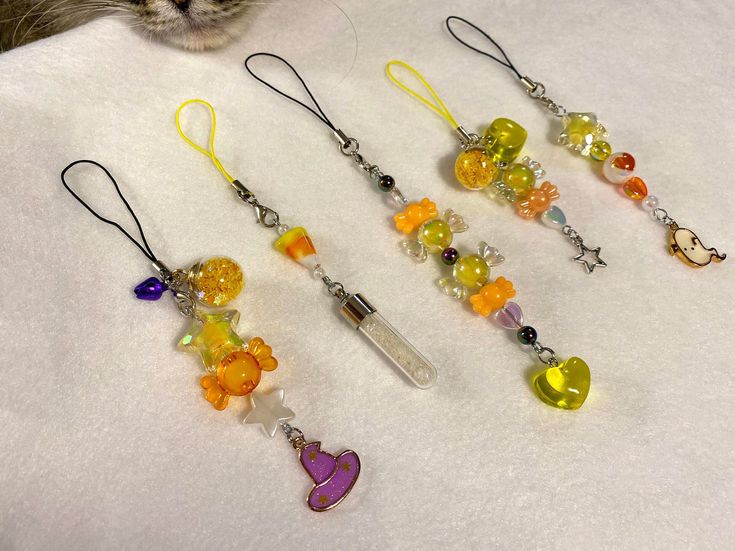 a cat is looking at some colorful bead necklaces on a white tablecloth