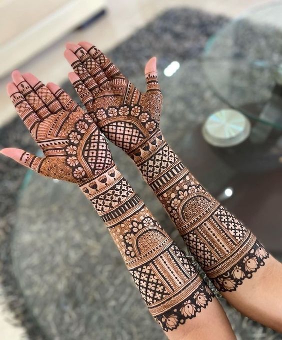 two hands with henna tattoos on them, one is showing off the intricate design