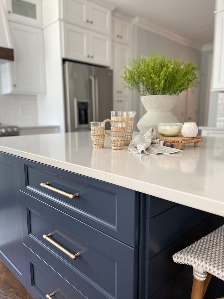 a kitchen island with white cabinets and blue drawers in front of the countertop is filled with dishes, cups and utensils