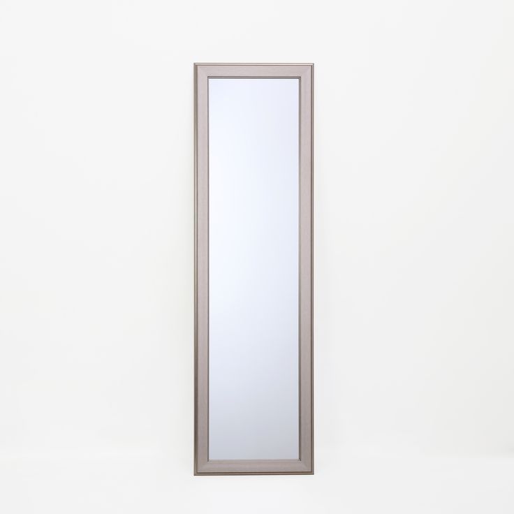 a tall mirror sitting on top of a white wall