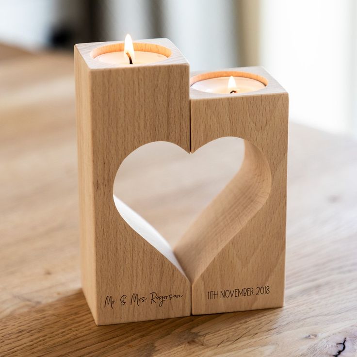 a wooden block with two candles in the shape of a heart