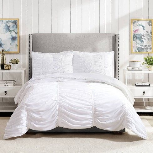 a bed with white comforter and pillows in a room next to two nightstands