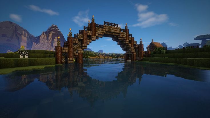 a bridge over a body of water with mountains in the backgrouds and blue sky