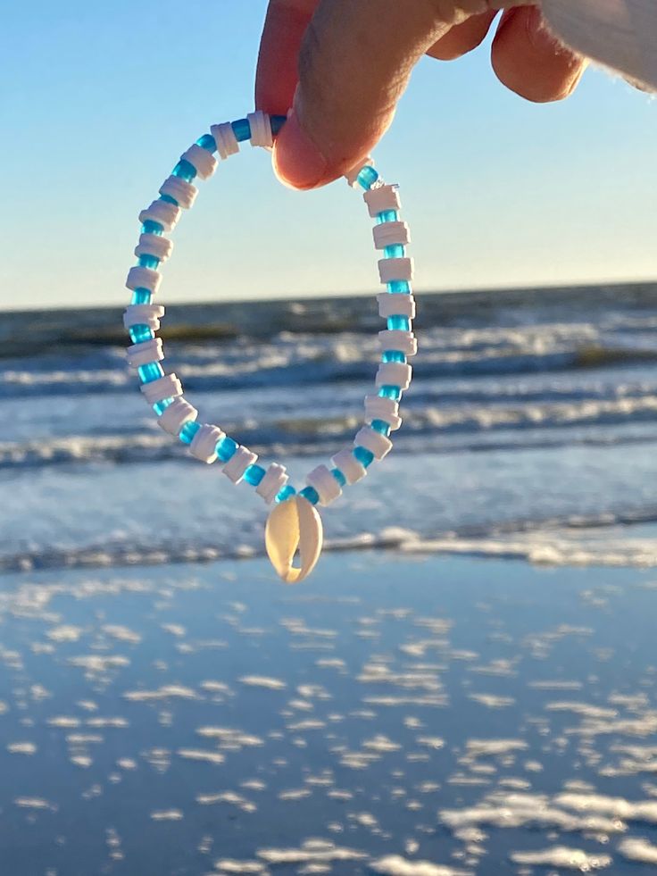 This bracelet has white beads and blue seed beads separating every white with a hanging seashell. Comes w/ 1 free sticker! White Shell Bracelets For Beach Season, Adjustable White Pearl Bracelet For Beach, Handmade White Pearl Bracelet For The Beach, Ocean-inspired White Beaded Jewelry, White Shell Friendship Bracelets For Vacation, White Round Beads Ocean-inspired Bracelets, Beaded Shell Strand Bracelets, White Strand Bracelets For Vacation, Blue Beaded Pearl Bracelet For Beach