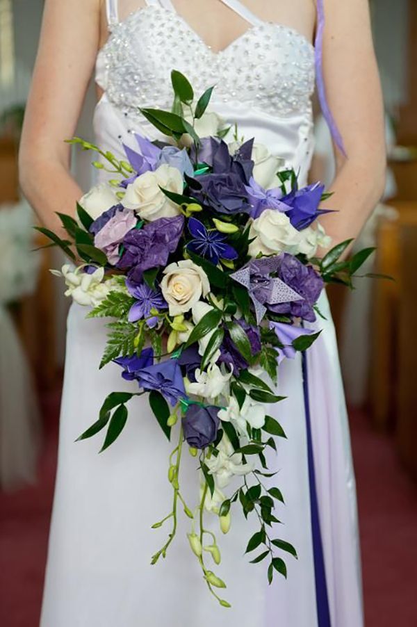 a woman in a white dress holding a purple and white bouquet