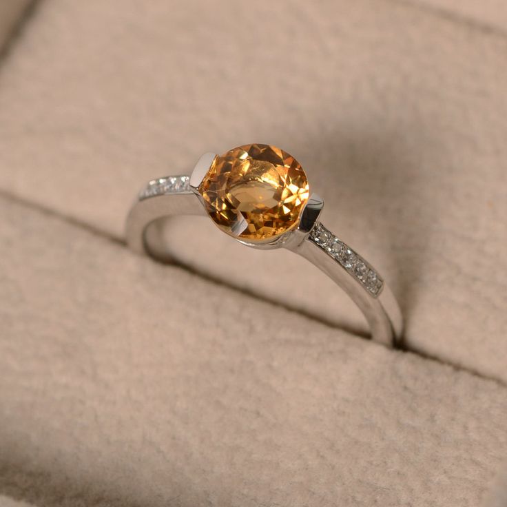 This ring features a 7mm round cut natural citrine and sterling silver finished with rhodium. Customization is available. It is made by hand, and it will take about 7 days to finish the ring after your payment is completed. Main stone: genuine citrine Citrine weight: Approx 1.40 ct Metal type: sterling silver finished with rhodium Accent stone: cz Customization is available, I also can make it with 14k solid gold (white or yellow or rose) and diamond accent stone, just feel free to contact me. A Promise Ring With Citrine Birthstone, Citrine Birthstone Ring With Gemstone For Promise, Citrine Gemstone Birthstone Ring For Promise, Orange Gemstone Ring In Sterling Silver, Sterling Silver Gemstone Ring In Orange, 14k White Gold Topaz Birthstone Promise Ring, Fine Citrine Jewelry For Promise, Sterling Silver Orange Gemstone Rings, Sterling Silver Rings With Orange Gemstone