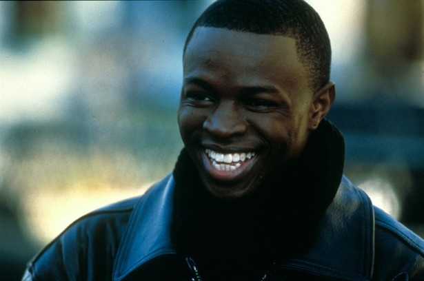 a close up of a person wearing a black jacket and smiling at the camera with a blurry background