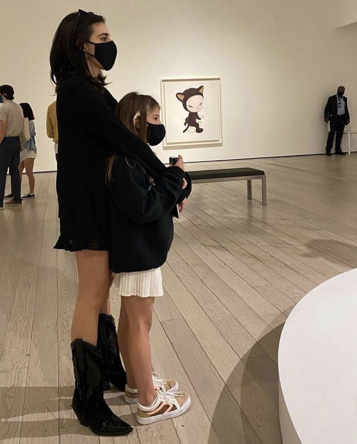 two women wearing masks in an art gallery