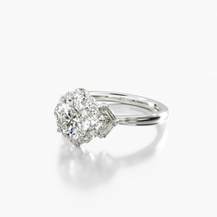 an oval diamond ring with two round diamonds on the band and shoulders, set in 18k white gold