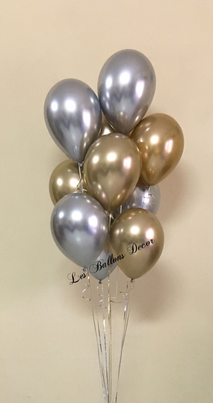 silver and gold balloons are in a clear vase