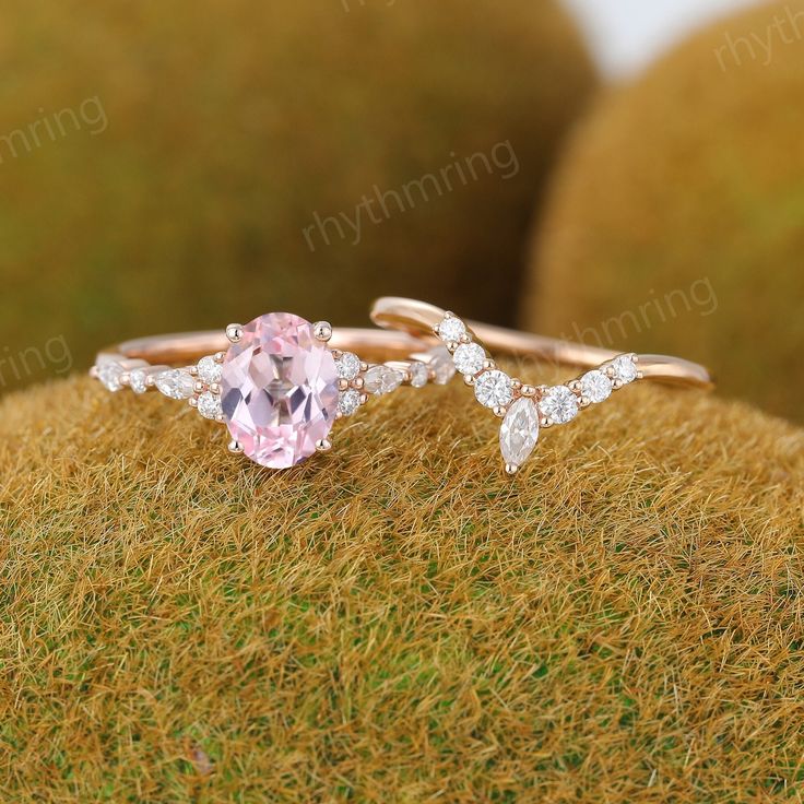 an engagement ring with a pink stone and diamond accents on top of mossy ground