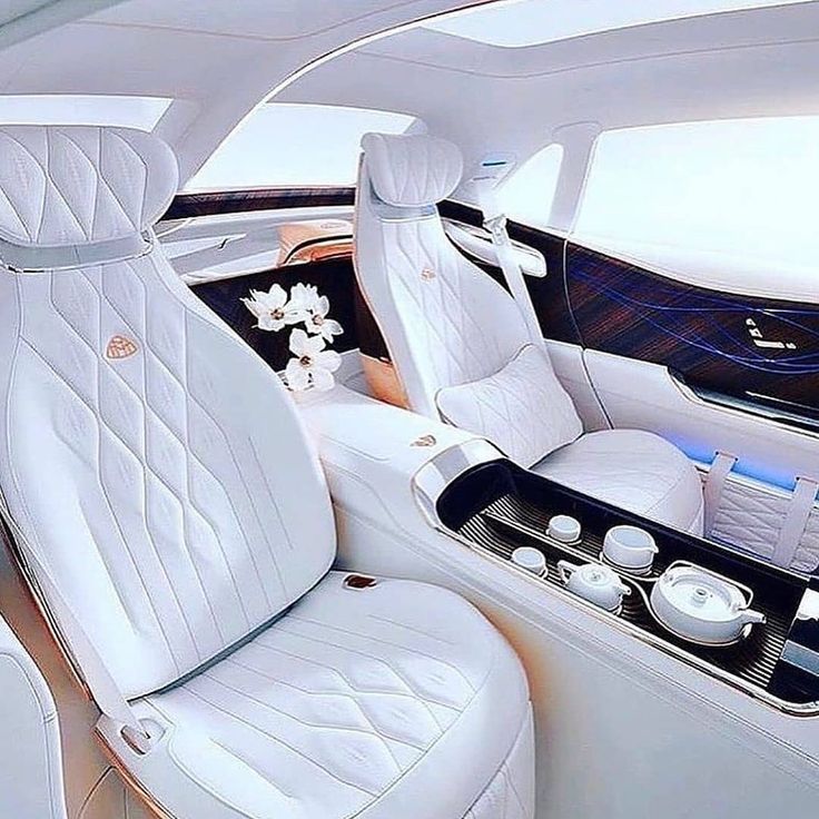 the interior of a luxury car with white leather seats and flowers in vases on the center console