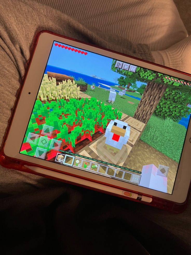 a person holding an ipad with a game on the screen in their lap, while they are playing minecraft