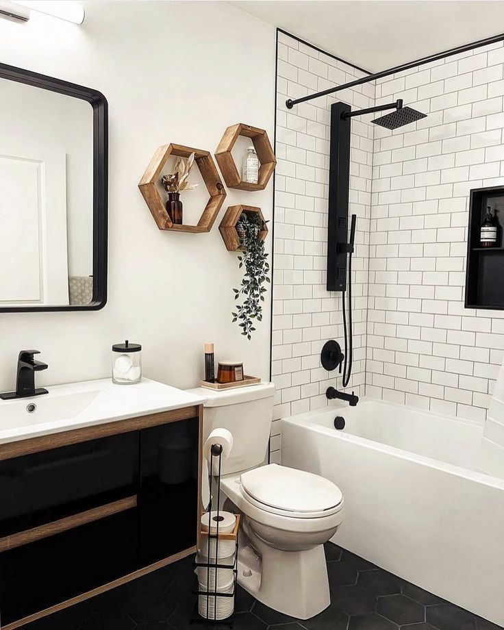 a bathroom with black and white tile, hexagonal mirror, sink, toilet and bathtub