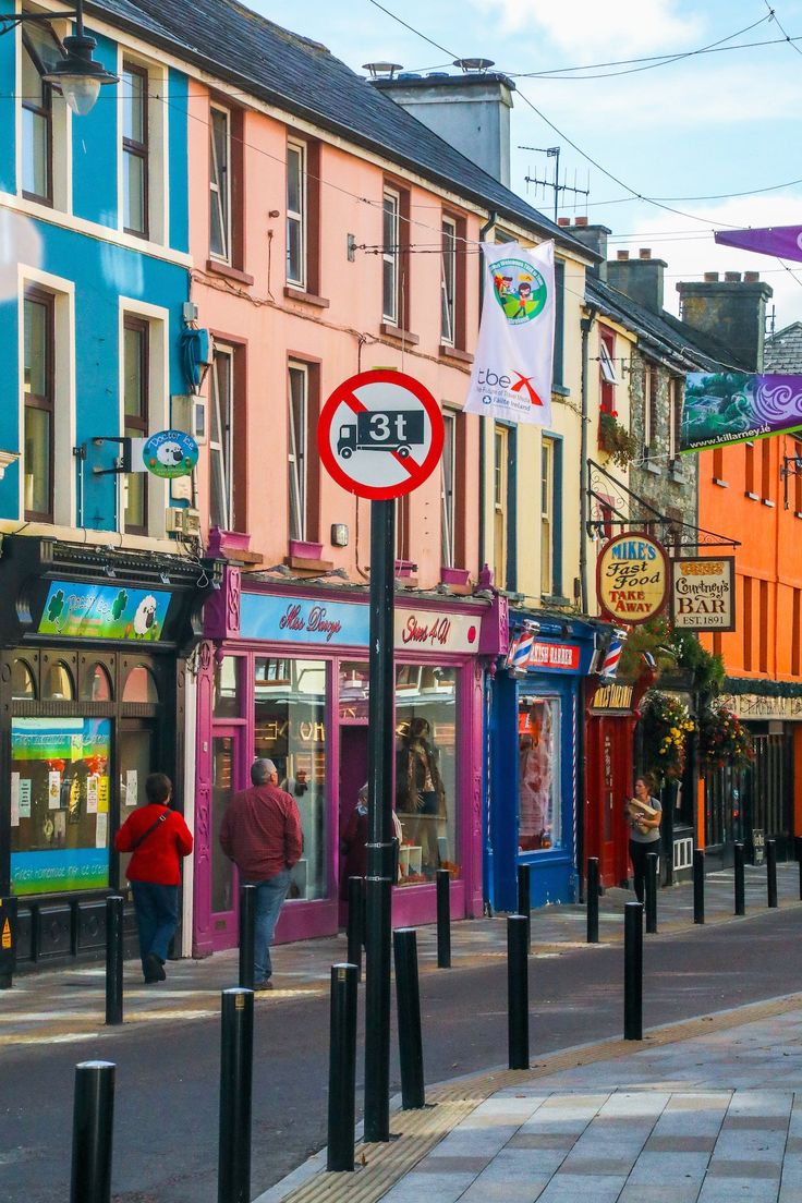 a city street filled with lots of shops and people walking down the sidewalk next to it