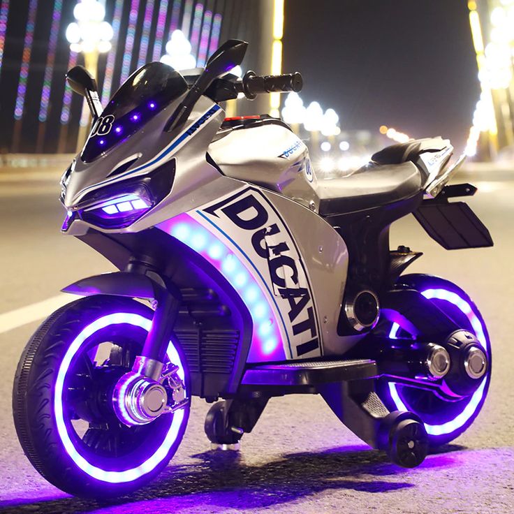 a white and black motorcycle with purple lights on it's tires is parked in the street