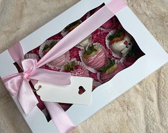 a box filled with chocolate covered strawberries and topped with a pink satin ribbon tied around the top