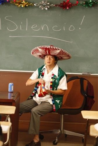 a man wearing a sombrero sitting in front of a blackboard