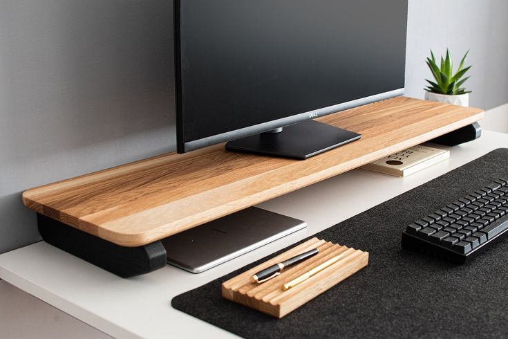 a flat screen tv sitting on top of a white desk next to a keyboard and mouse