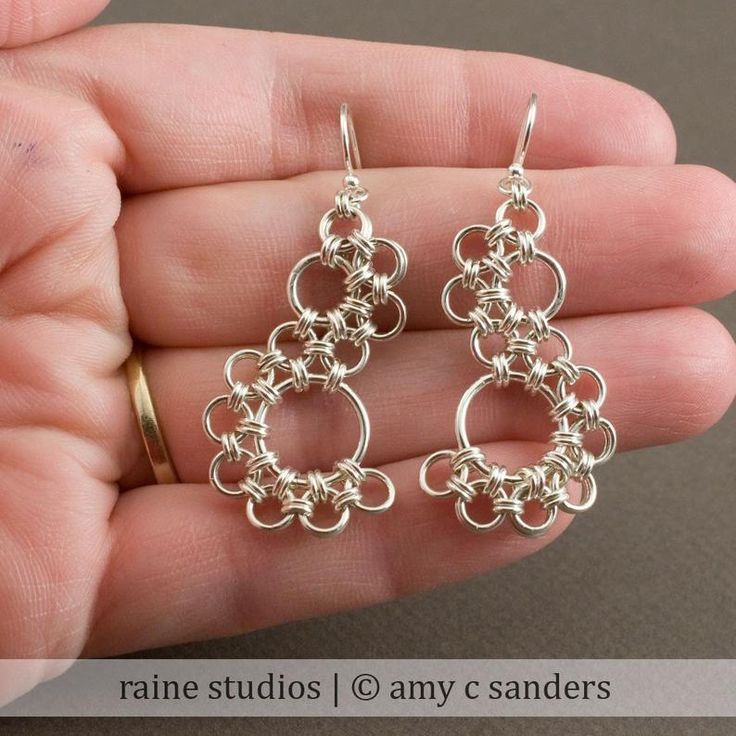 a pair of silver earrings in the shape of an o - ring on a person's hand