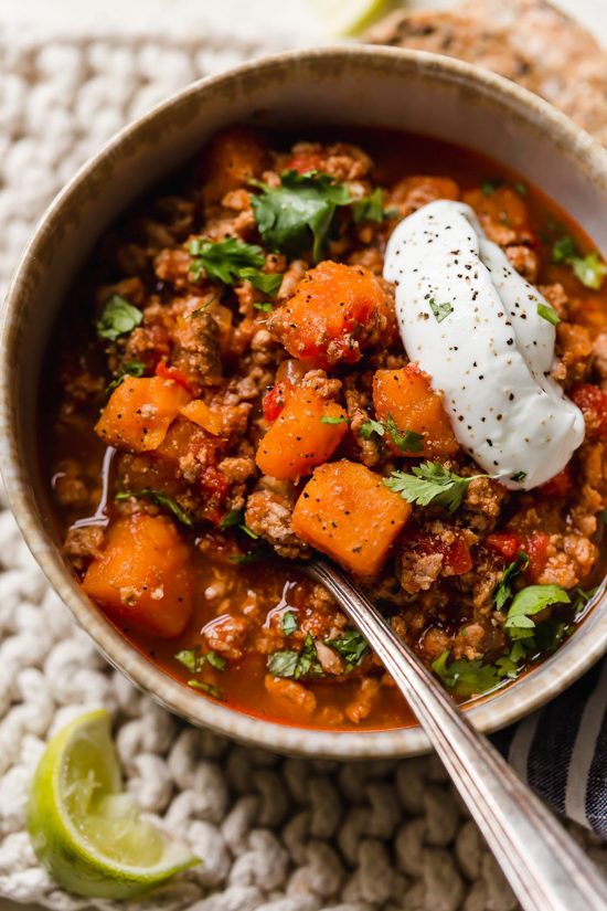 a bowl filled with meat and vegetables on top of a table next to a spoon