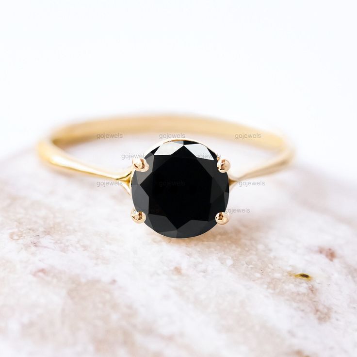 a black diamond ring sitting on top of a rock