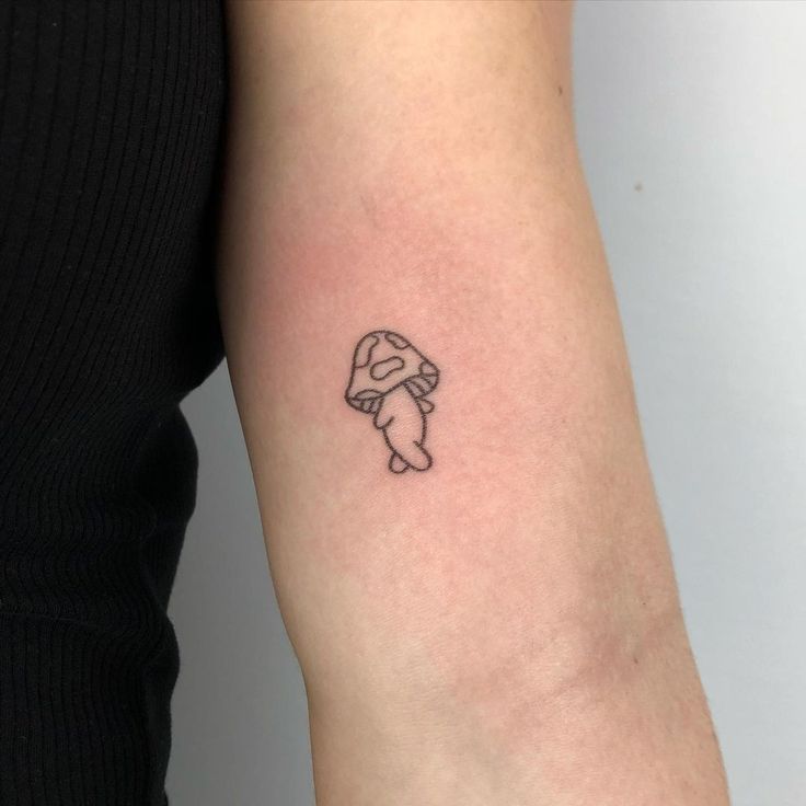 a small tattoo on the arm of a woman with a black and white image of a person's head