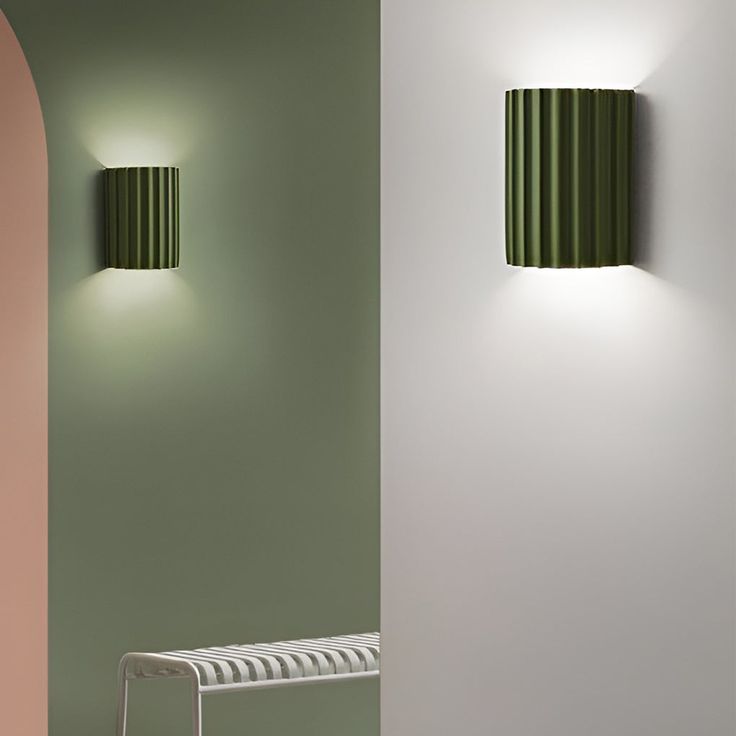 two green lamps on the wall next to a white bench