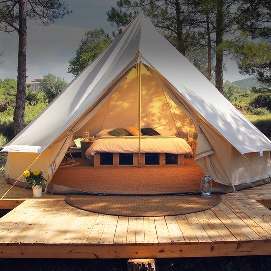 a tent with a bed in it sitting on top of a wooden platform