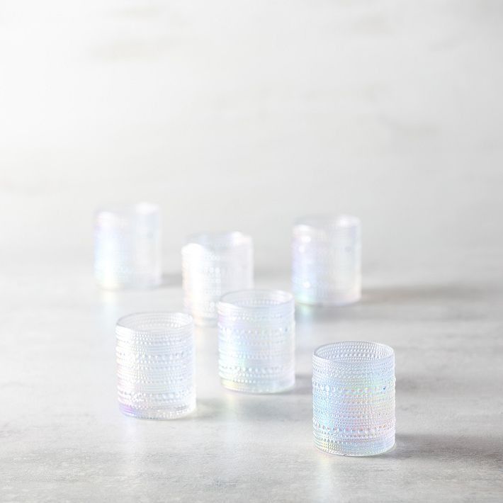 six clear shot glasses sitting on top of a white countertop next to each other