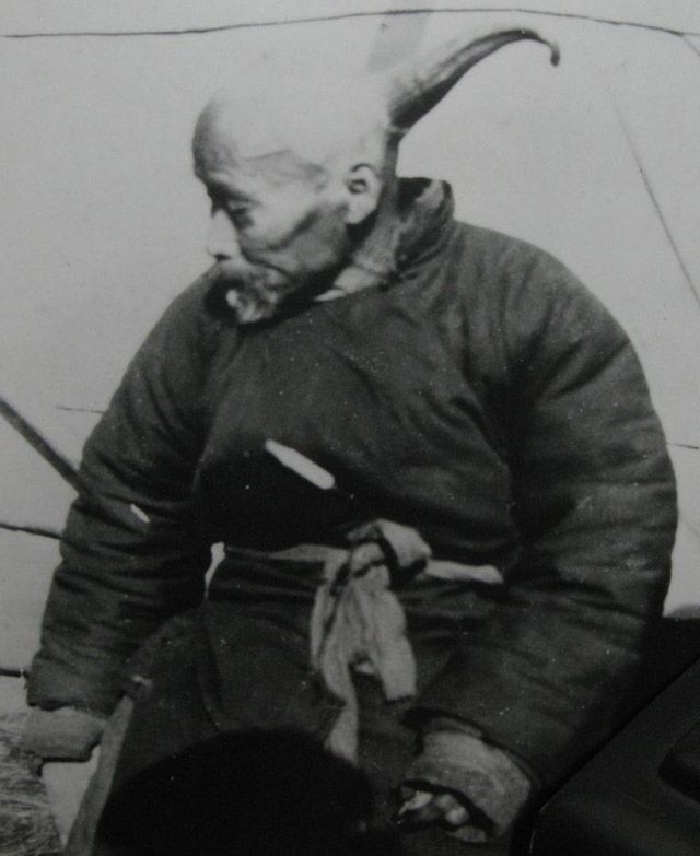 an old black and white photo of a man with horns on his head sitting down