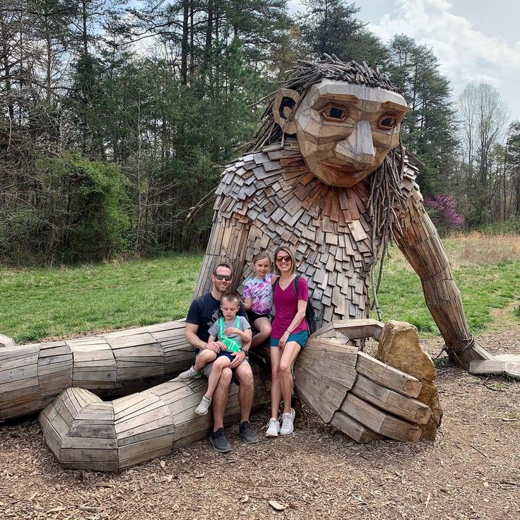 a family poses in front of a wooden statue