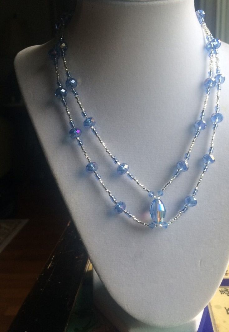 a necklace with blue glass beads on a mannequin