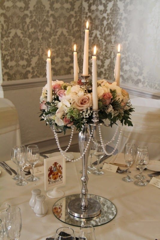 a centerpiece with candles and flowers on a table