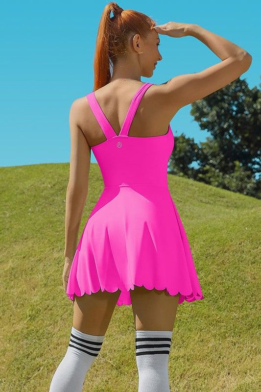 a woman in a pink dress is standing on the grass with her hands behind her head