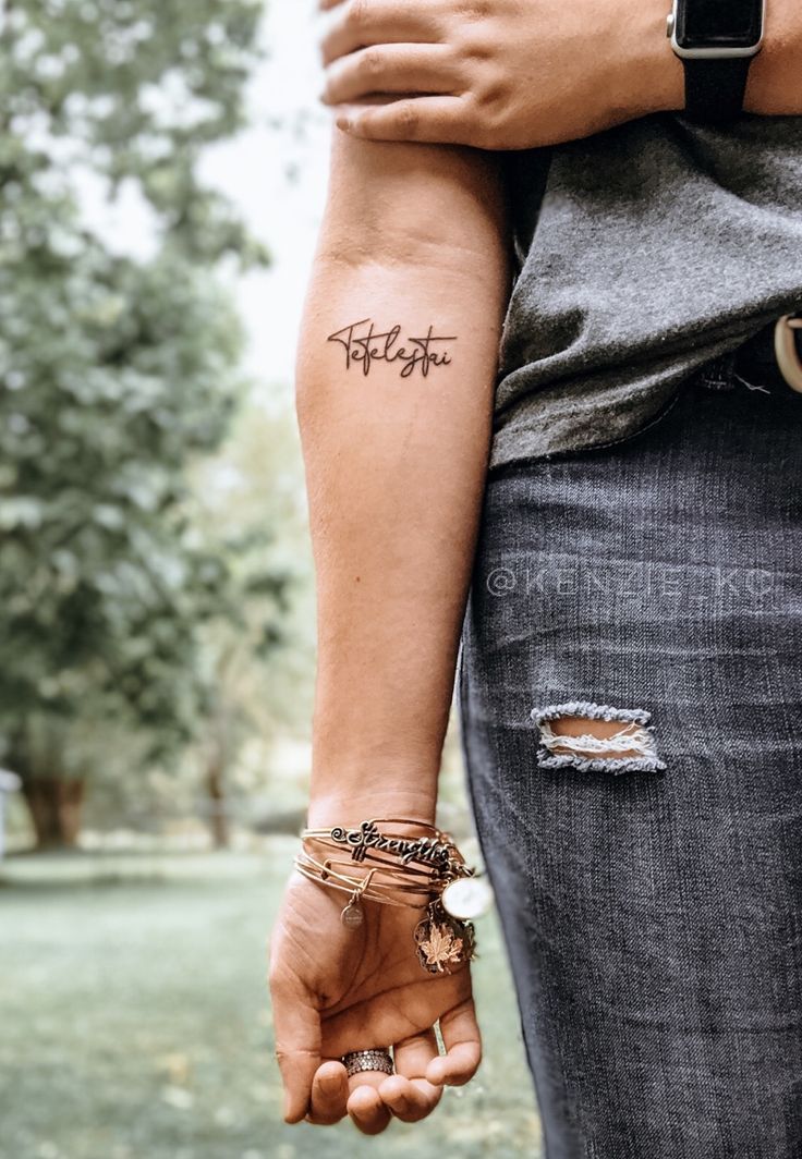 two people holding hands with tattoos on their arms