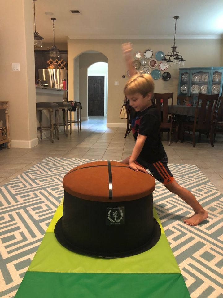 a young boy playing with a large hat on the floor